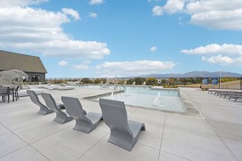 A pool surrounded by grey benches on a sunny day.at The Garrison Luxury Apartment Homes, Colorado, 80817